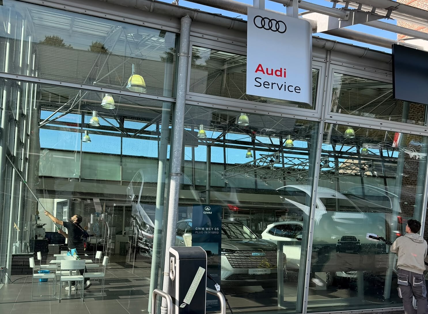 Zwei Mitarbeiter von Expert Reinigung bei der Glasreinigung an einem Autohaus