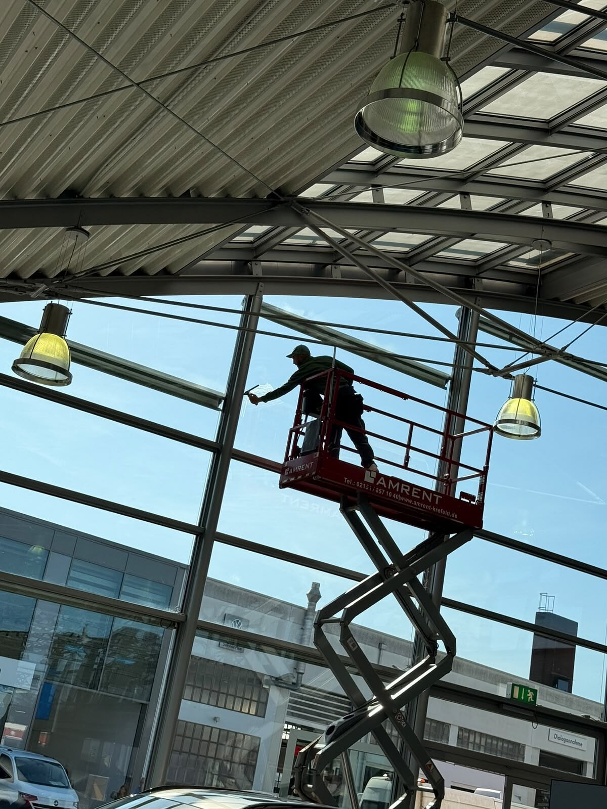 Mitarbeiter von Expert Reinigung reinigt eine Glasfront von der Scherenbühne aus